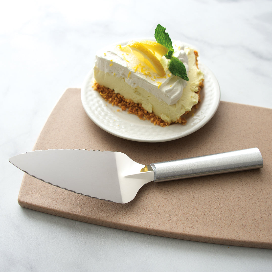 A silver handled Serrated Pie Server next to a piece of lemon merengue pie.