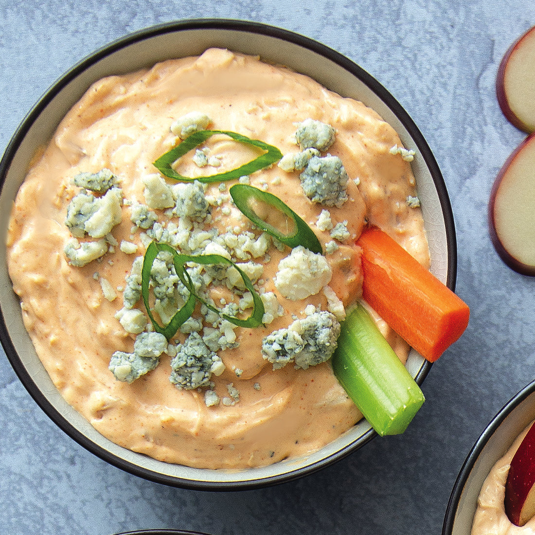 A bowl of Buffalo Dip with celery and carrot slices
