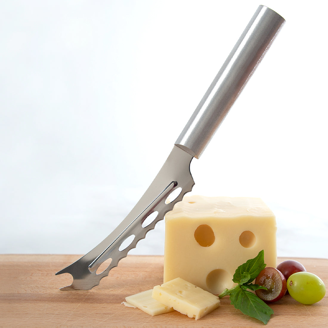 Cheese knife with a block of cheese and grapes on a wooden board