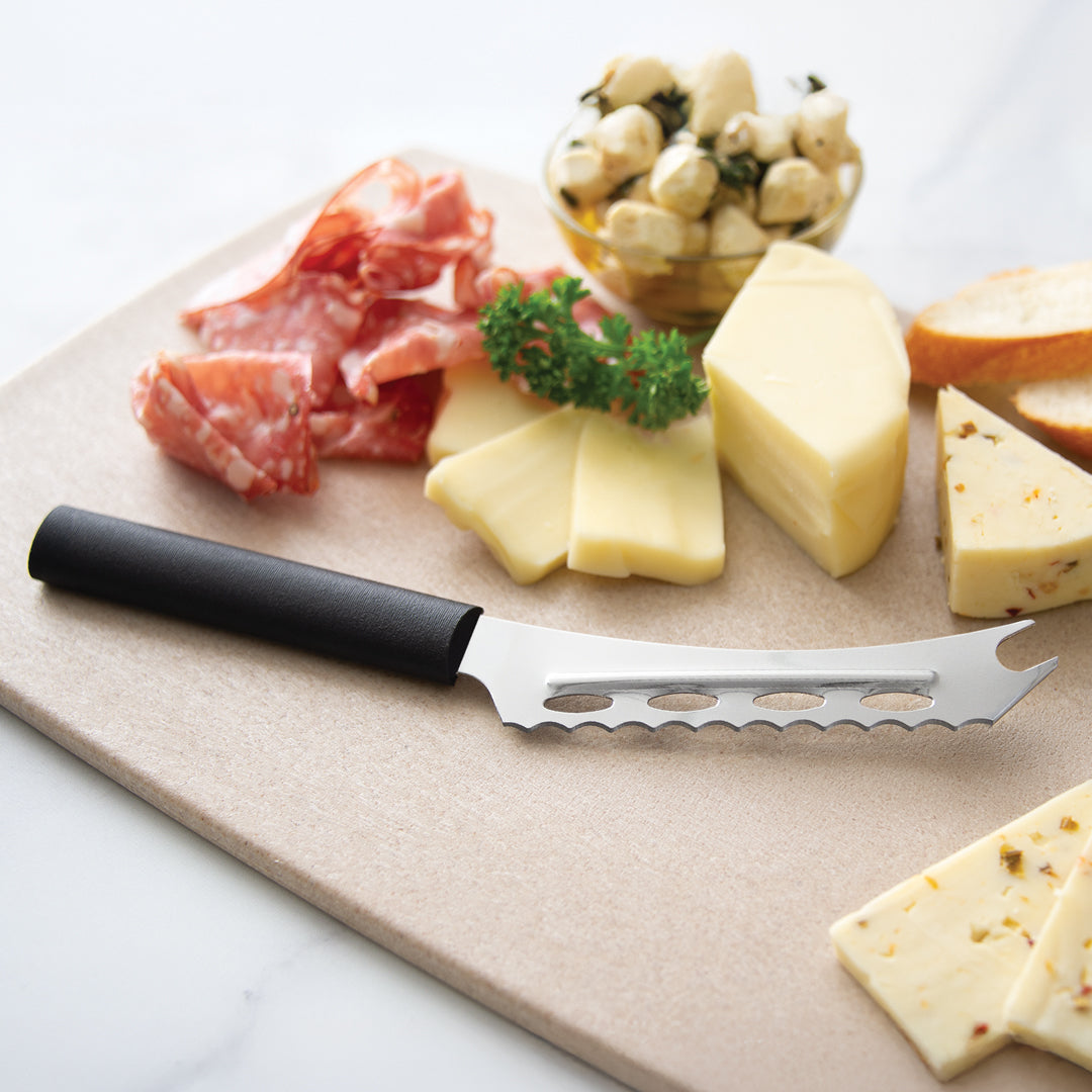 Cheese platter with sliced cheese, cured meats, and a cheese knife on a wooden board.