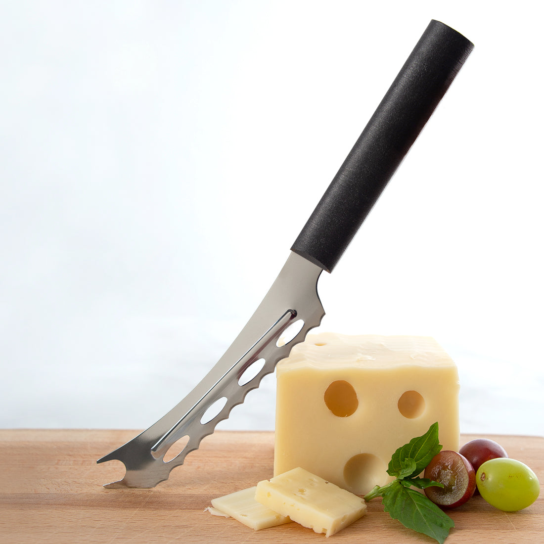 Cheese knife with a block of cheese and grapes on a wooden board