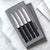 Four Serrated Steak Knives Gift Set on a marble countertop with silver ribbons