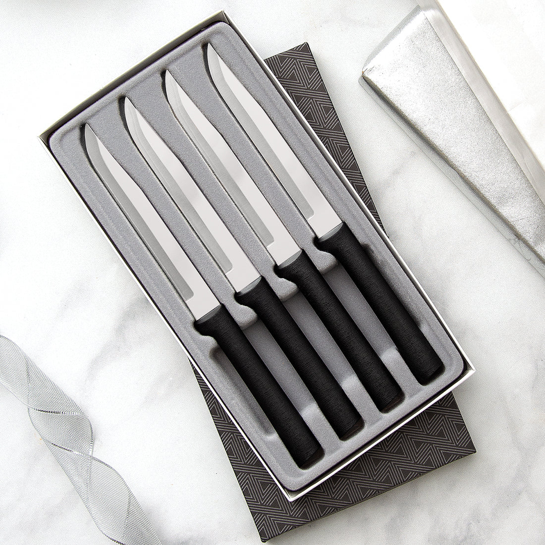 Four Utility Steak Knives Gift Set on a marble countertop with silver ribbons