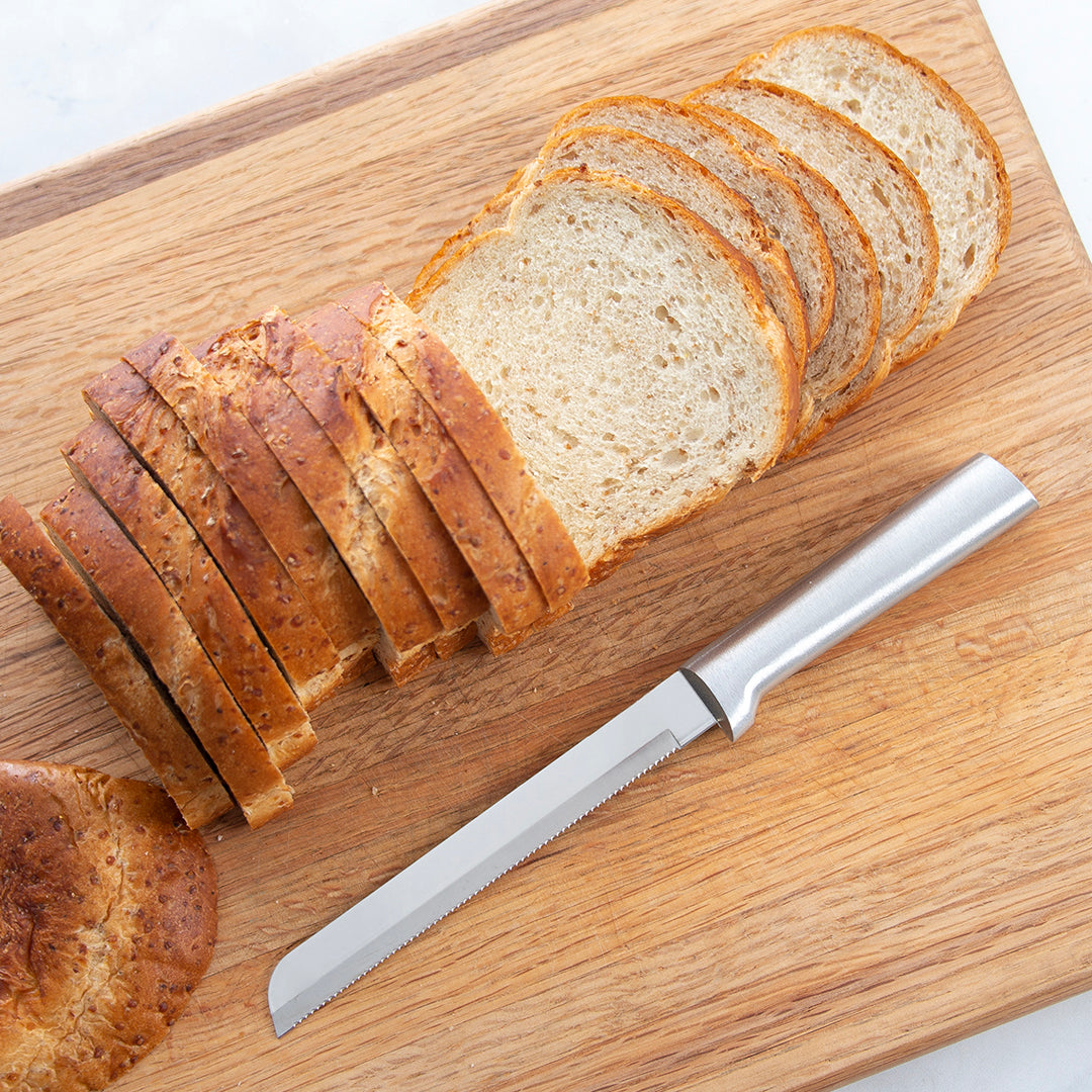 Two bread knives next to a sliced loaf of French Bread