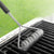 Rada Cutlery Grill Brush laying on top of grate on grill cleaning it.