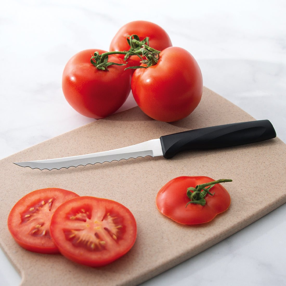 An Anthem Wave Tomato Slicer on a tan cutting board with sliced tomatoes