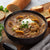 A bowl of Beef Stroganoff Soup on a wood cutting board next to slices of bread