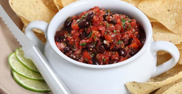 The silver handled tomato slicer with a bowl of bl
