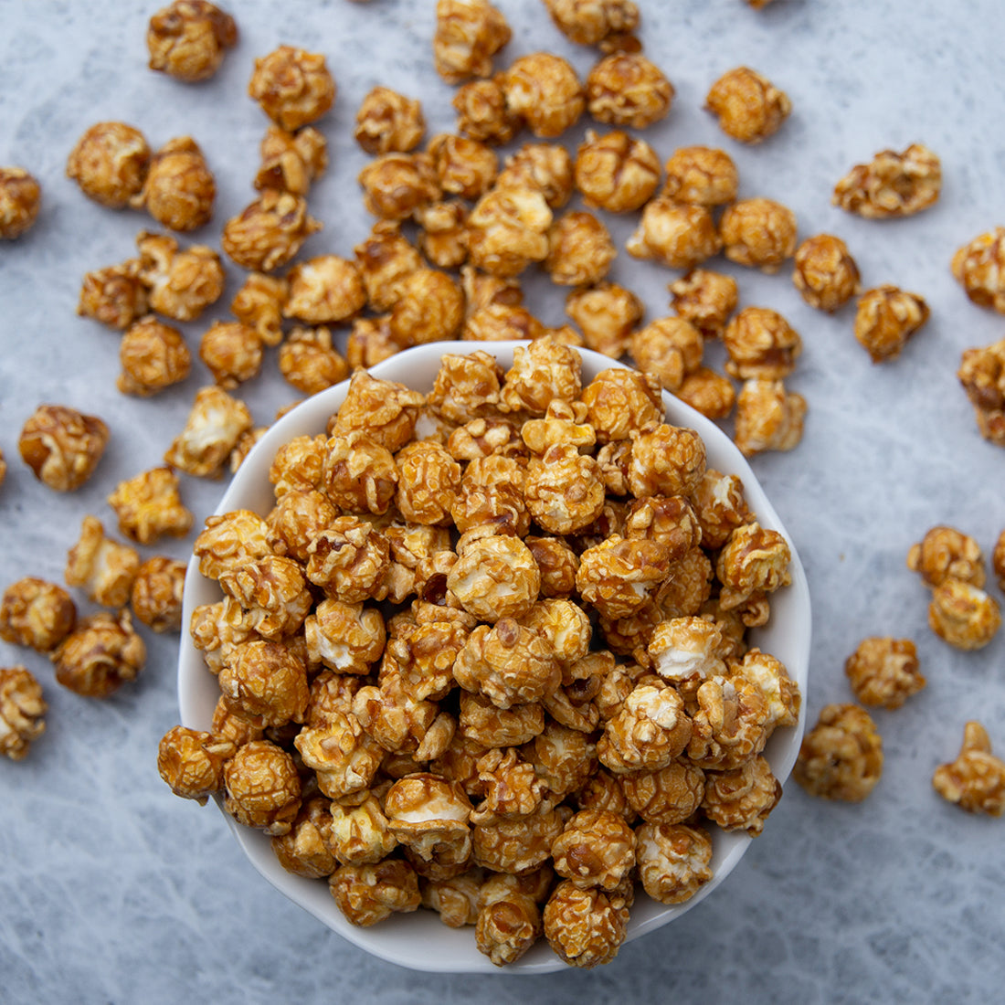 Old-fashioned caramel popcorn in a bowl and laying around the bowl.