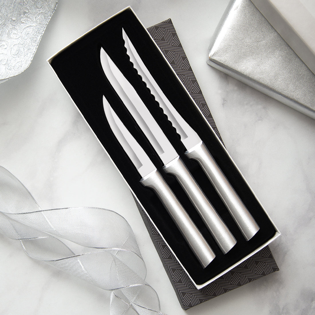 A Cooking Essentials Gift Set on a marble countertop with silver ribbons.