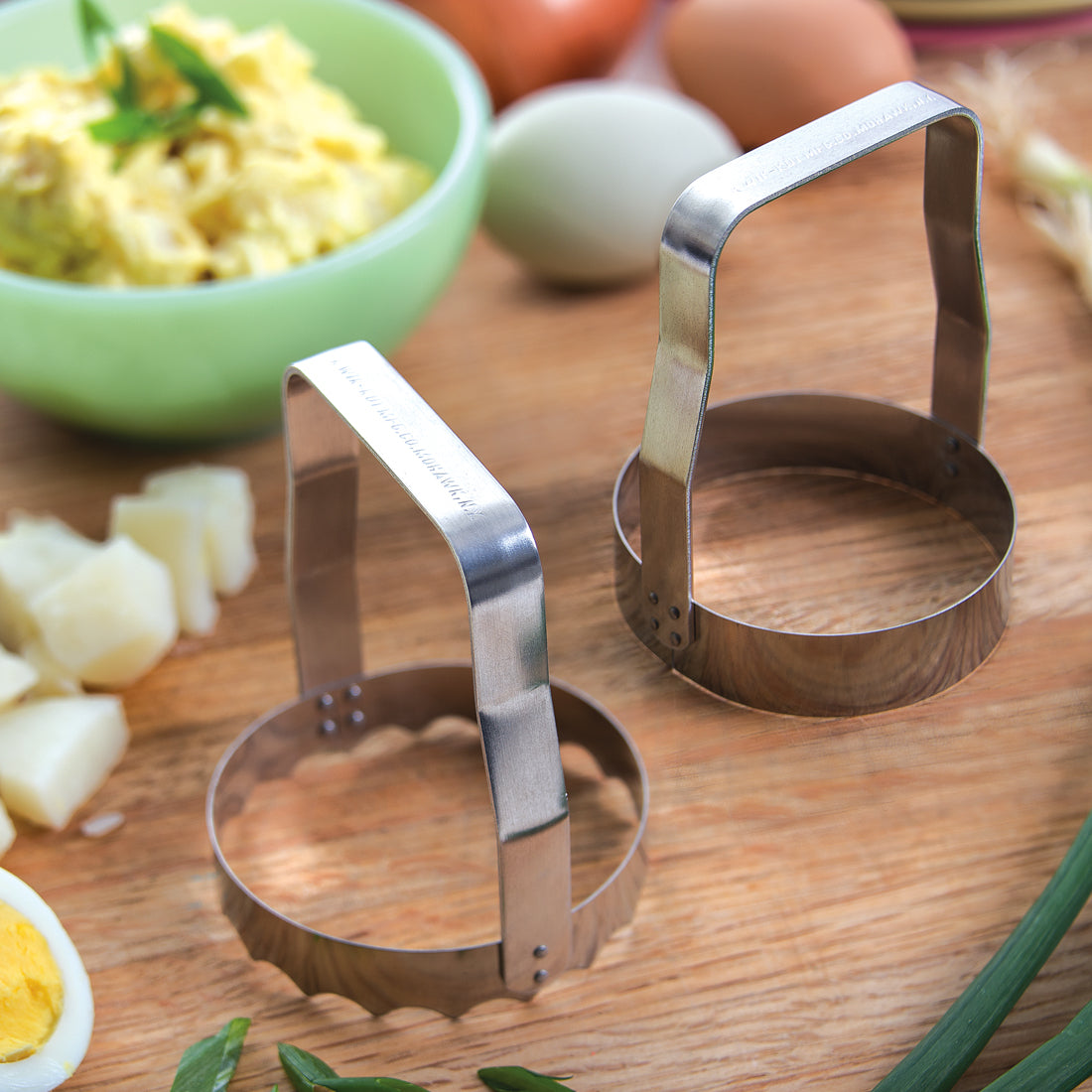A Plain and a Serrated Food Chopper next to a bowl of egg salad.