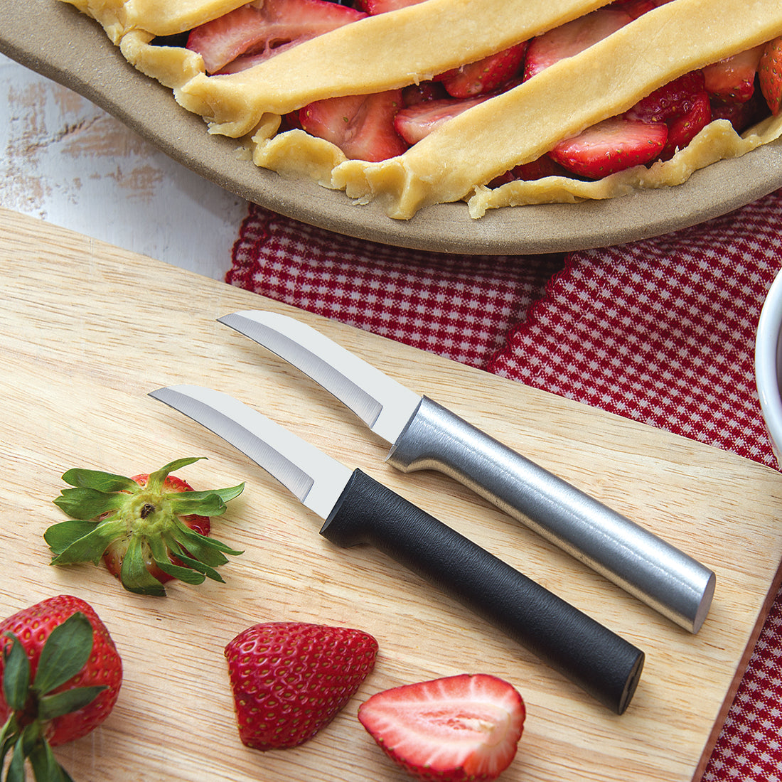 Two Granny Paring Knives on a wood cutting board with strawberries