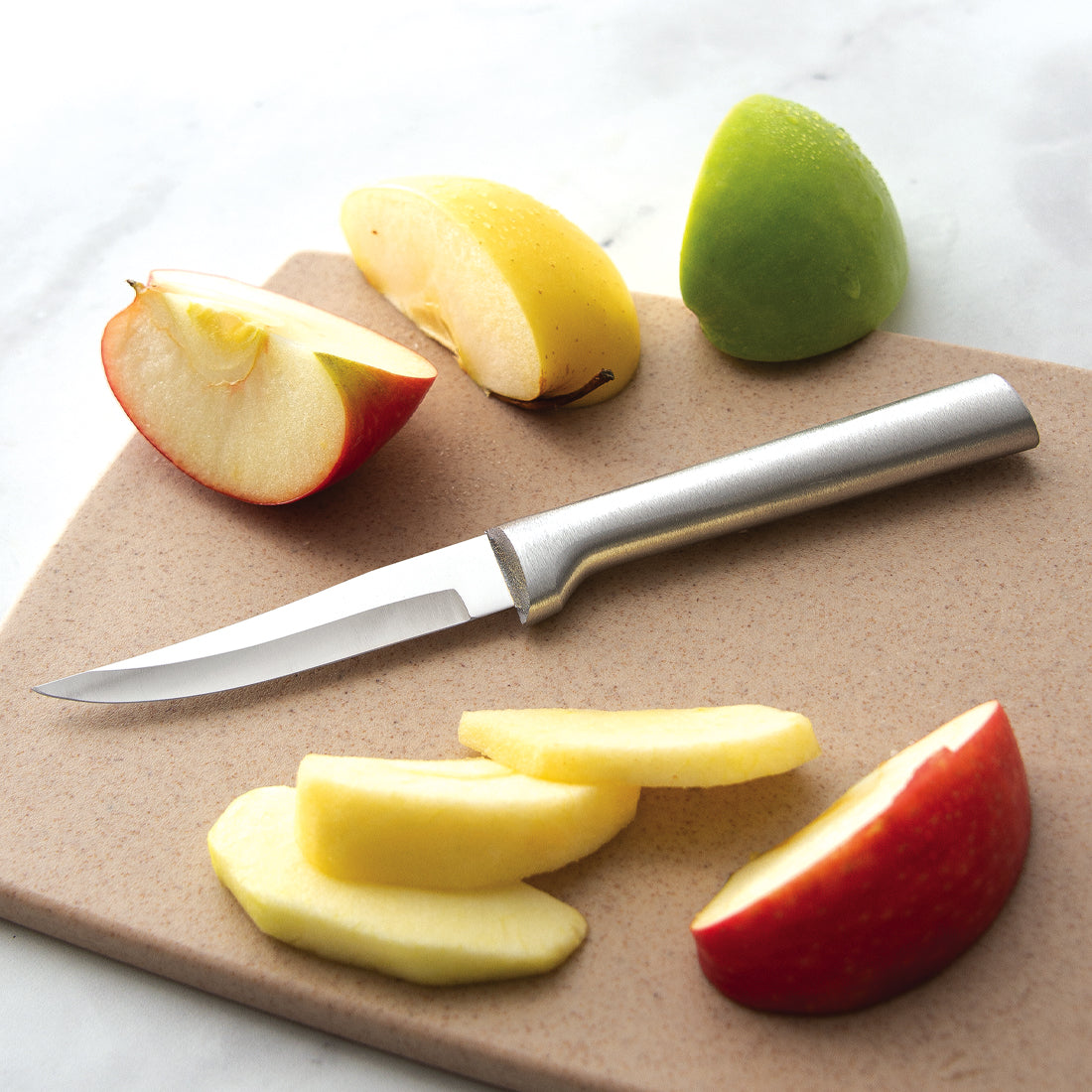 A Heavy Duty Paring knife next to sliced apples.