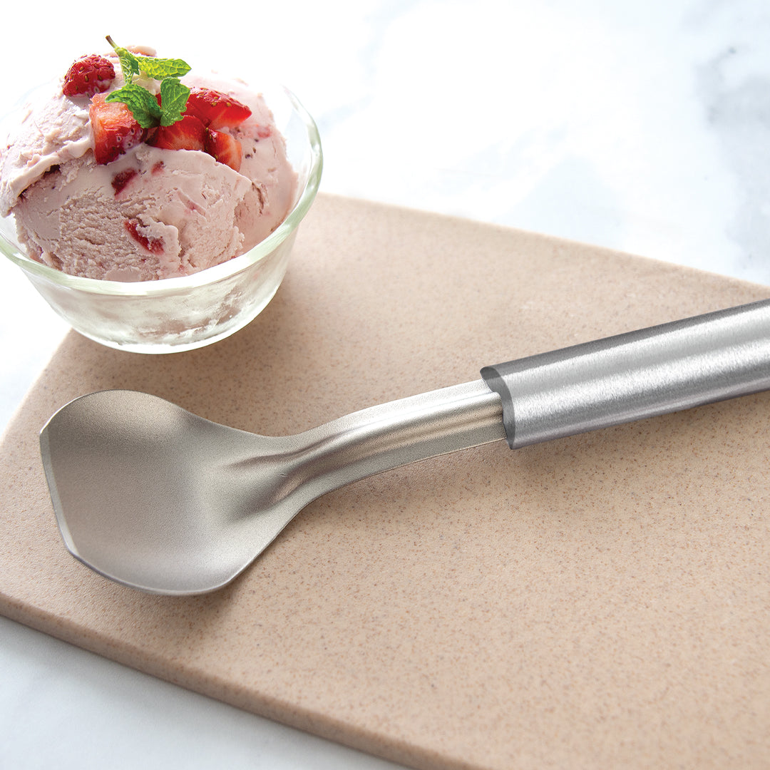 An Ice Cream Scoop next to a bowl of strawberry ice cream