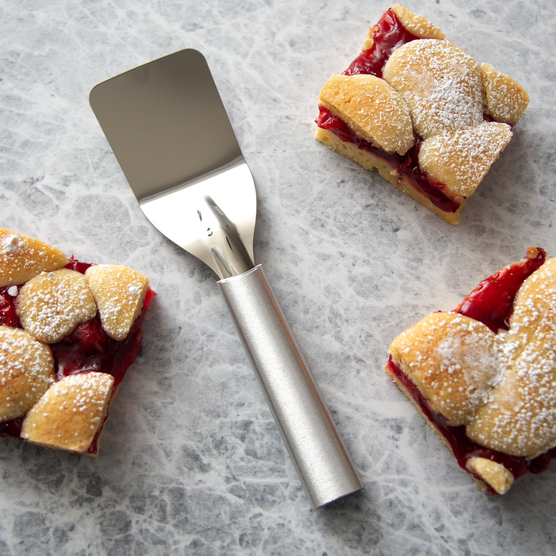 A Mini Server next to squares of cherry bars on a marble countertop.