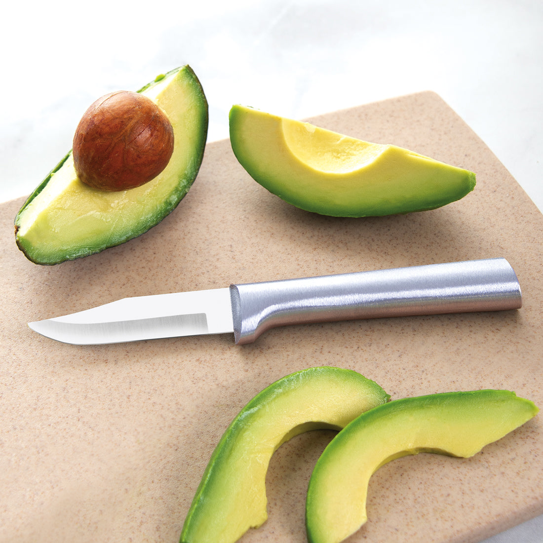 A Peeling Paring knife next to a sliced avocado.