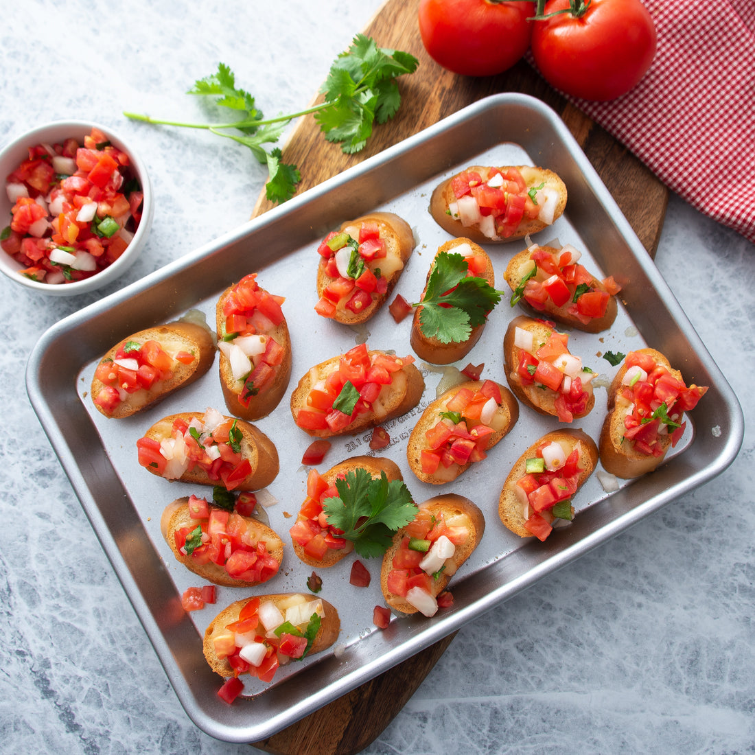 Quarter Sheet Pan full of baguette slices topped with diced tomatoes.