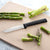 Silver handled Regular Paring knife next to sliced asparagus on a tan cutting board