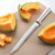 Silver handled Serrated Slicer next to sliced cantaloupe.