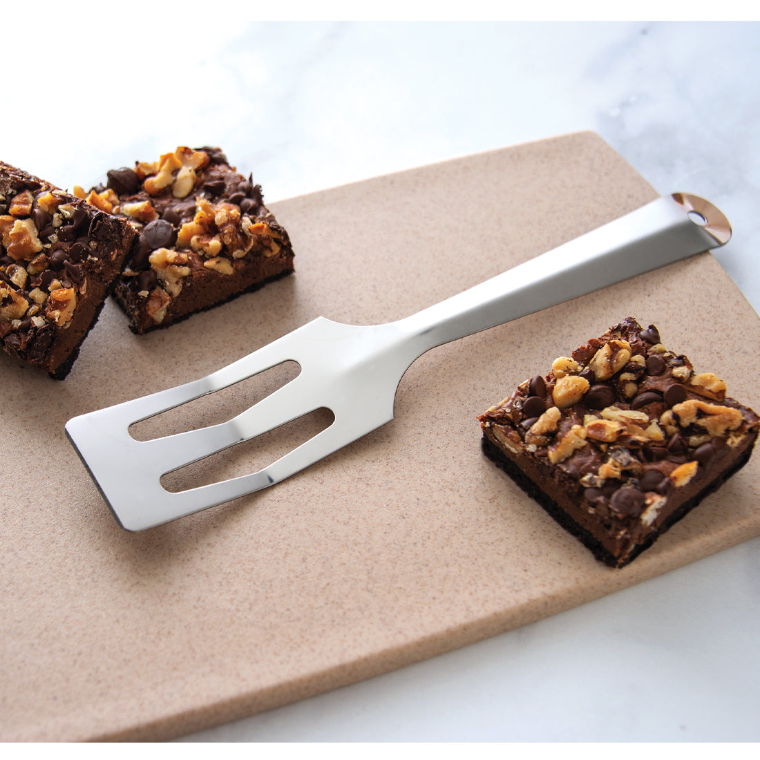 Serverspoon on a marbled countertop surrounded by brownies.