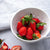 Small 1 Qt. Colander full of strawberries next to a blue and white napkin.