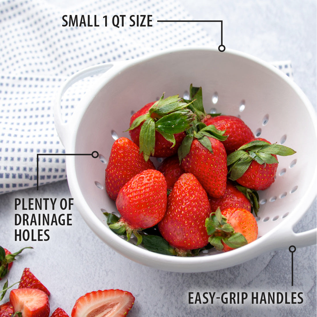 Small 1 Qt. Colander full of strawberries next to a blue and white napkin.
