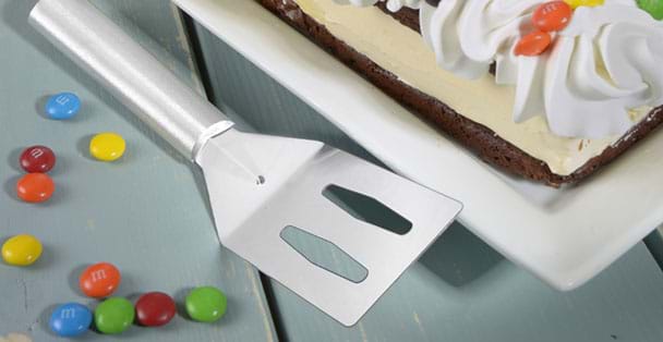 The silver handled spatula laying next to the gian