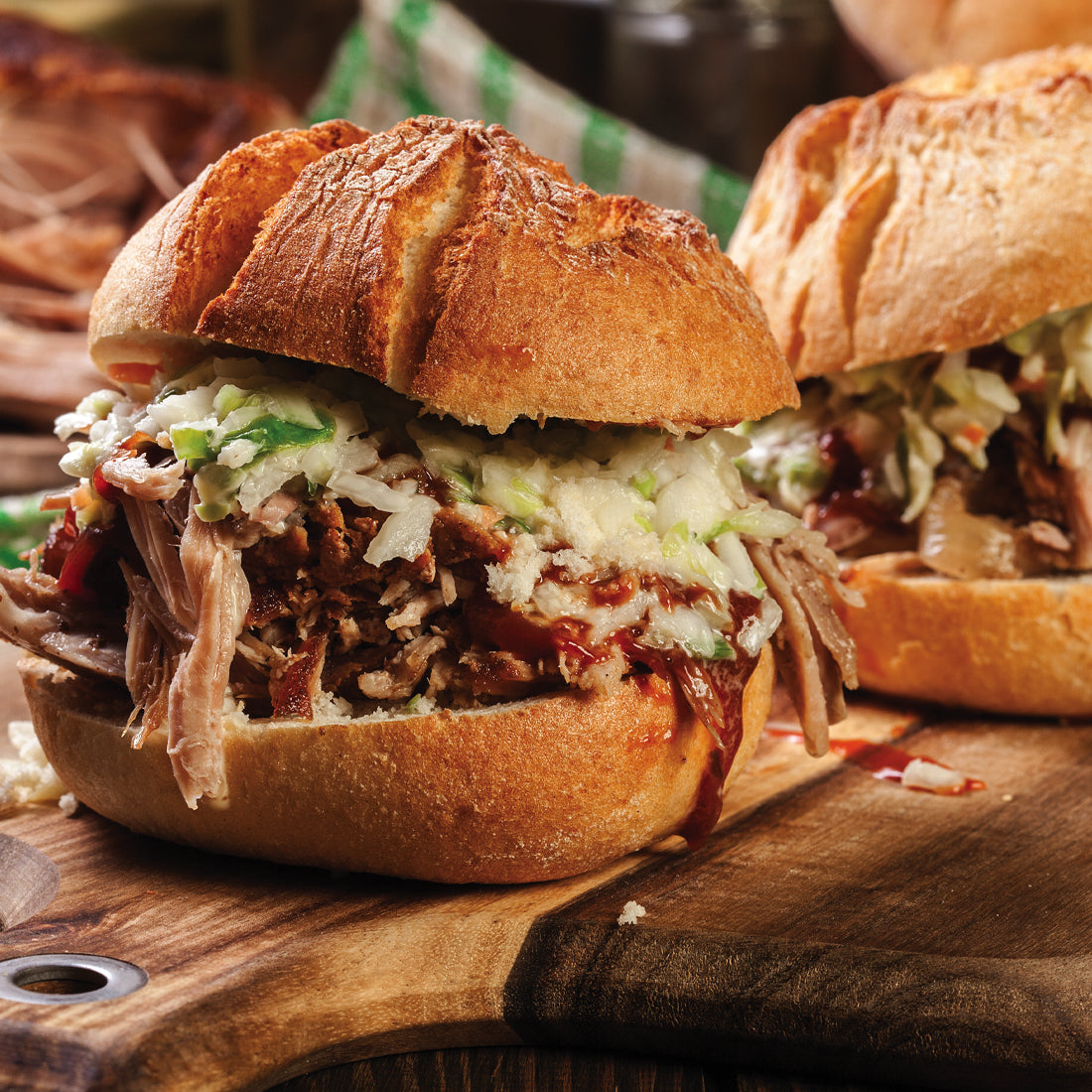 A pulled pork sandwich with barbeque sauce on a wood cutting board