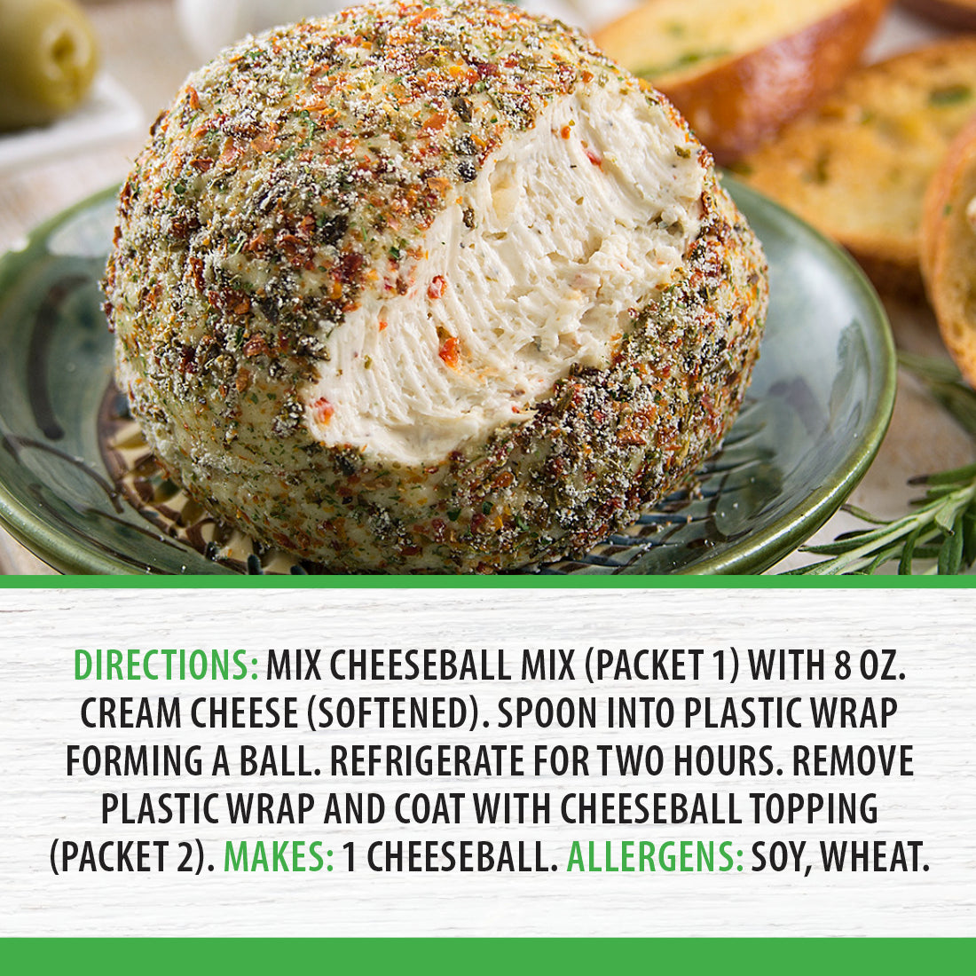 A Tuscan Herb Cheeseball on a green plate next to garlic, bread, olives, and fresh herbs.