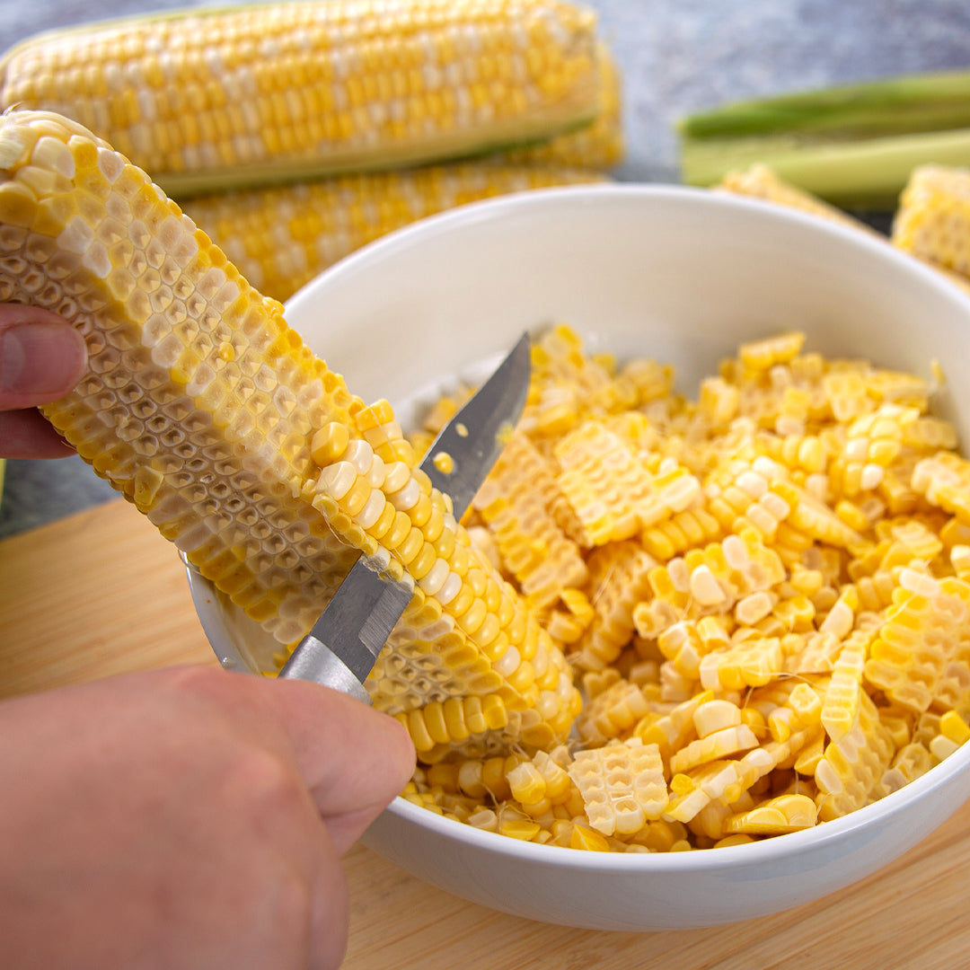 Rada&#39;s Utility/Steak with silver handle cutting corn into a bowl for canning.